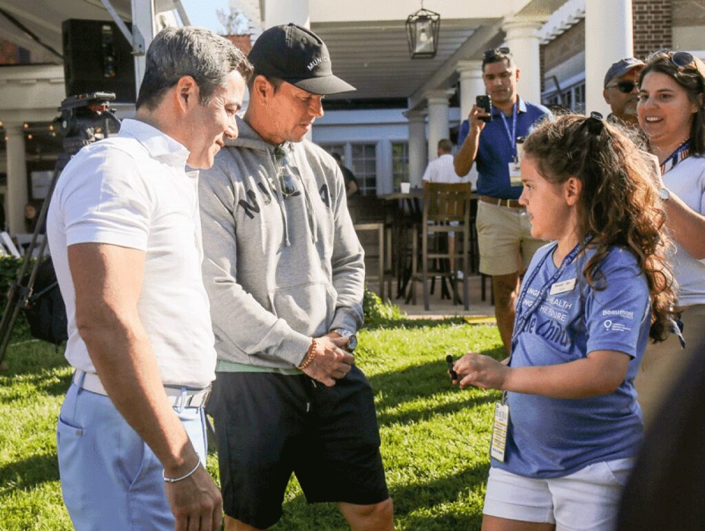 Mila Sikes, 8, of Sterling Heights, talks with Mark Wahlberg and Jay Feldman at the third annual Feldman Automotive Children’s Miracle Celebrity Invitational at Detroit Golf Club Aug. 28.