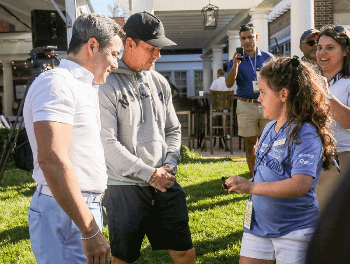 Mila Sikes, 8, of Sterling Heights, talks with Mark Wahlberg and Jay Feldman at the third annual Feldman Automotive Children’s Miracle Celebrity Invitational at Detroit Golf Club Aug. 28.
